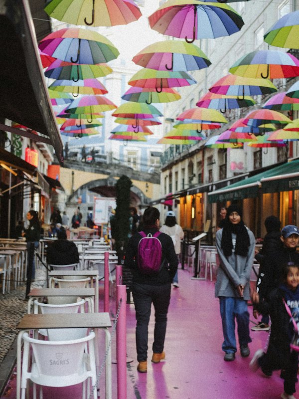 People walking on a street under colorful umbrellas