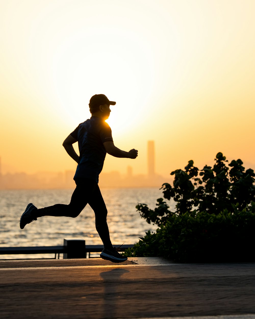 A runner on a waterfront path at golden hour